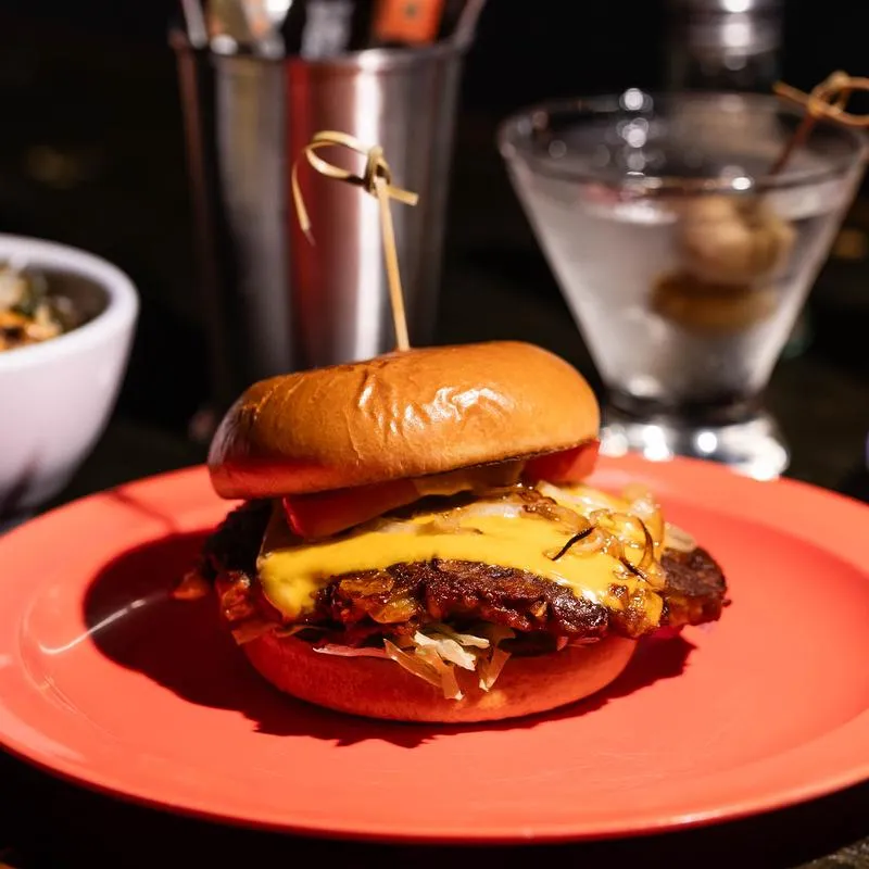 A juicy cheeseburger with caramelized onions on a red plate.