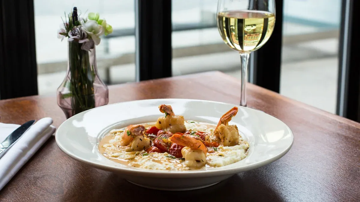 Shrimp and grits dish with white wine on a wooden table.