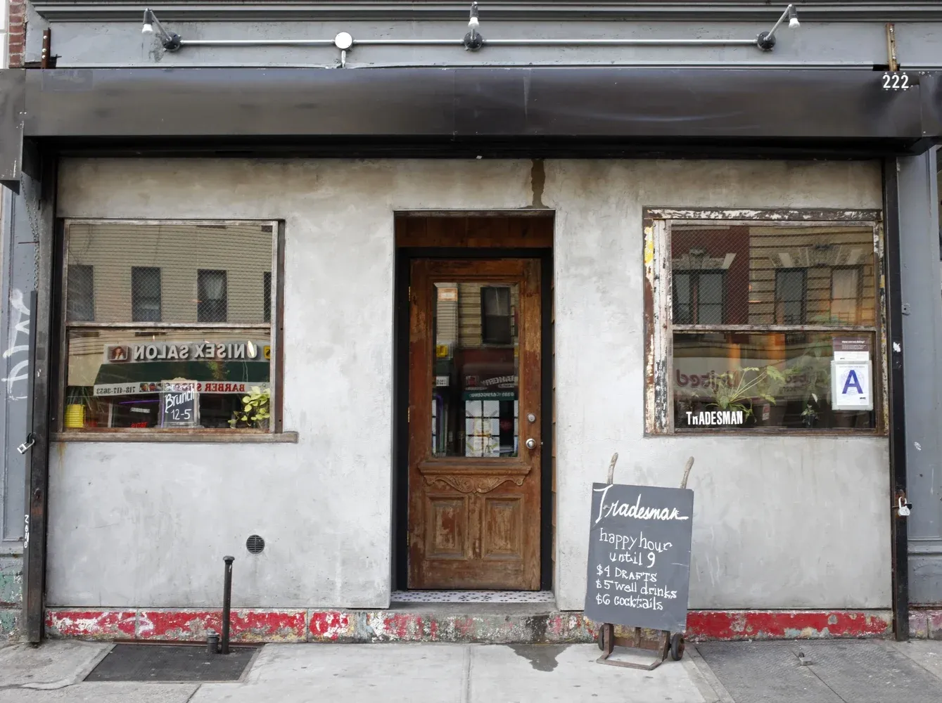 A light gray building with a wooden door between two window displays.