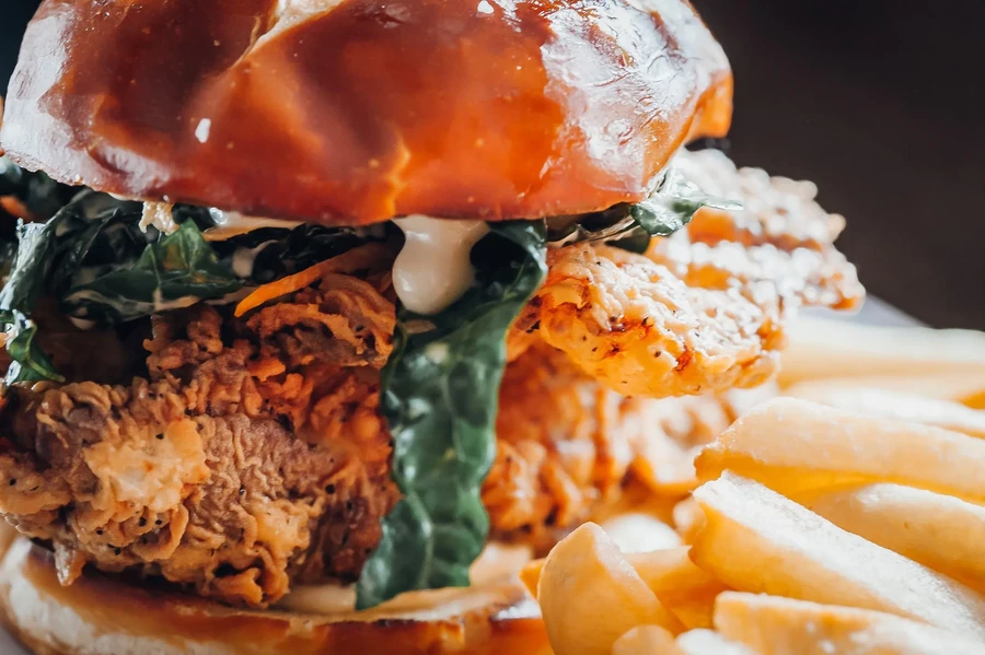 A close-up of a chicken burger with fries on the side.