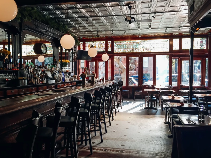 An empty bar and restaurant with high ceilings and large windows.