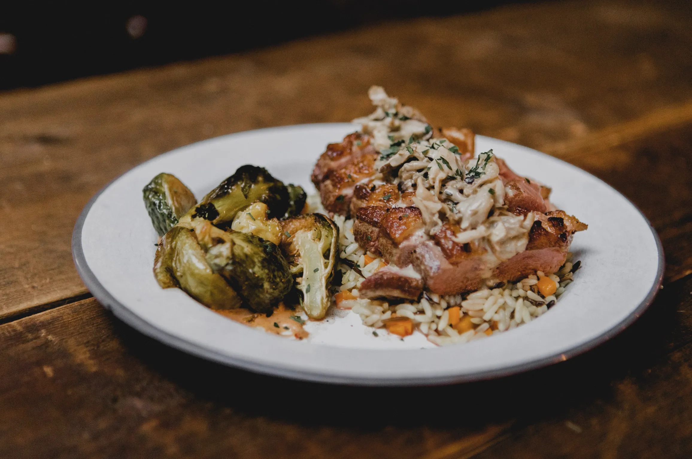 Close-up of duck breast with mushroom sauce, rice, and roasted Brussels sprouts.
