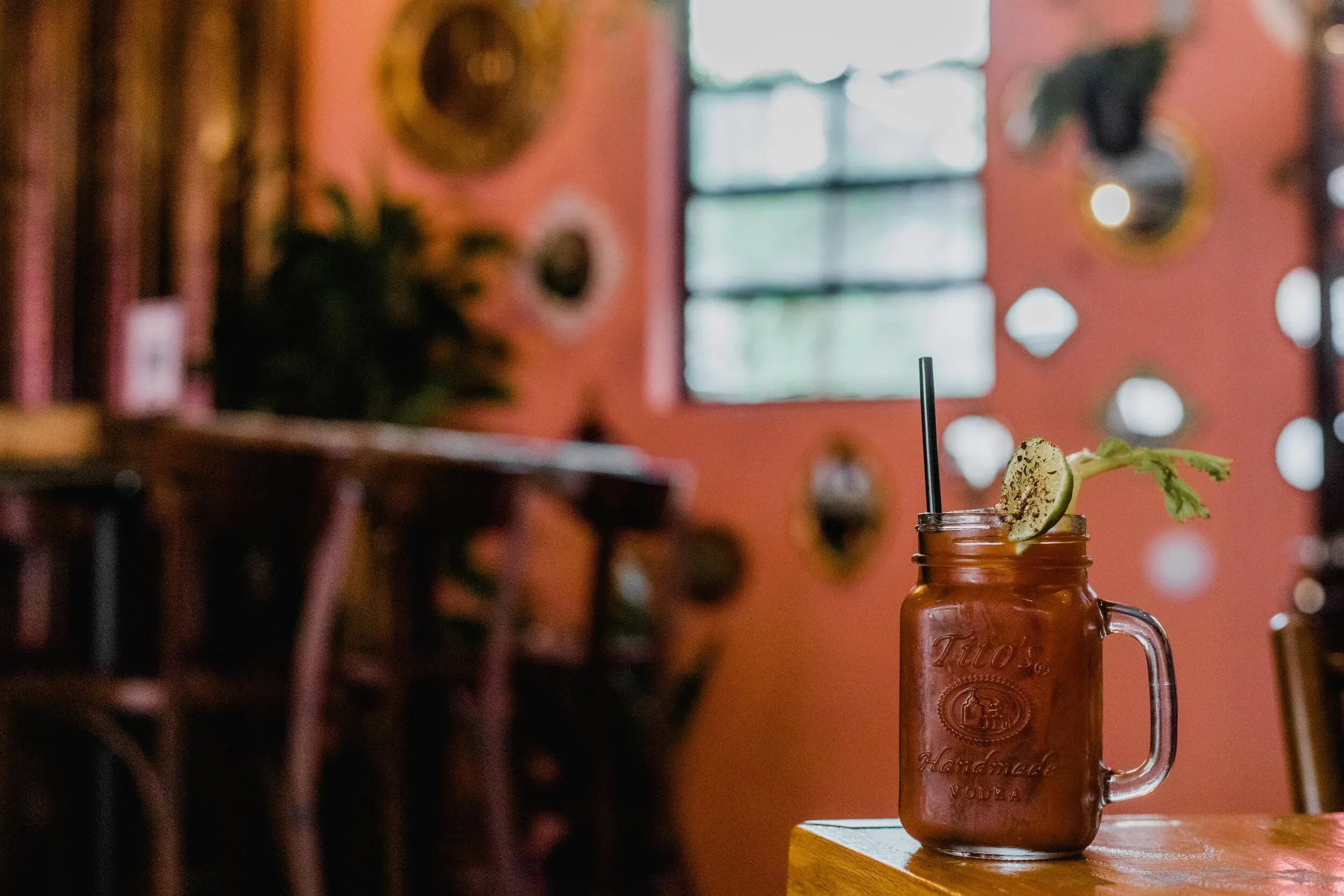 Tito's vodka drink in a mason jar, garnished with lime and celery.