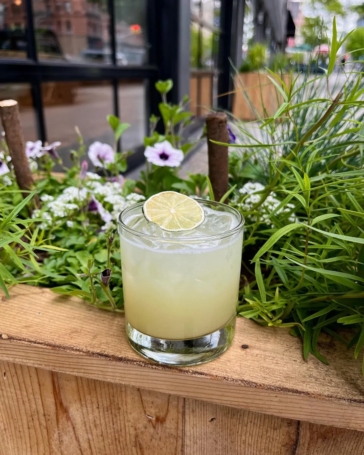 A glass of light green drink with a lime slice on a wooden surface.