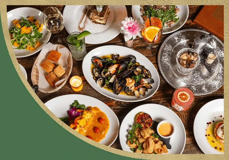 An overhead shot of a wooden table laden with various Italian dishes.