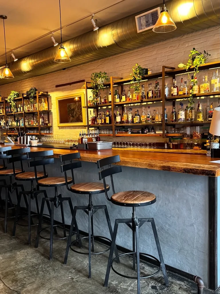 An inviting bar interior with wooden counter and industrial-style bar stools.