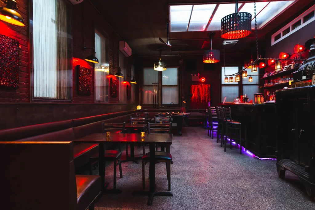A dimly lit bar and restaurant with red and purple lighting.