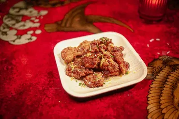 A white square plate of fried chicken on a red table.