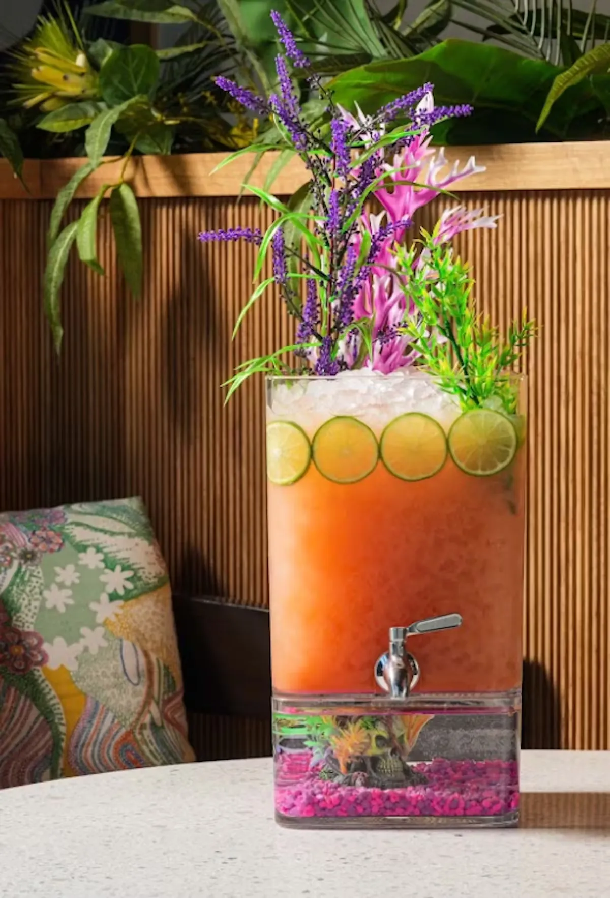 Orange drink dispenser with faux aquarium base and floral garnish.