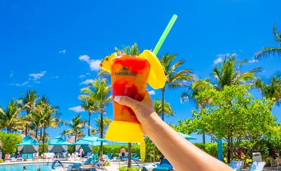 Layered Landshark tropical drink with pineapple, held at a sunny resort.