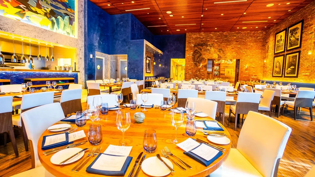 Upscale restaurant interior: impeccably set tables, blue wall, and brickwork.