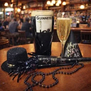 Guinness, champagne, and New Year's Eve party accessories on a wooden table.