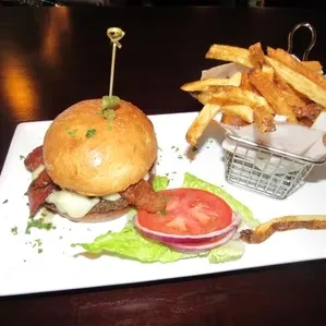Gourmet burger with brioche bun, cheese, bacon, and fries.