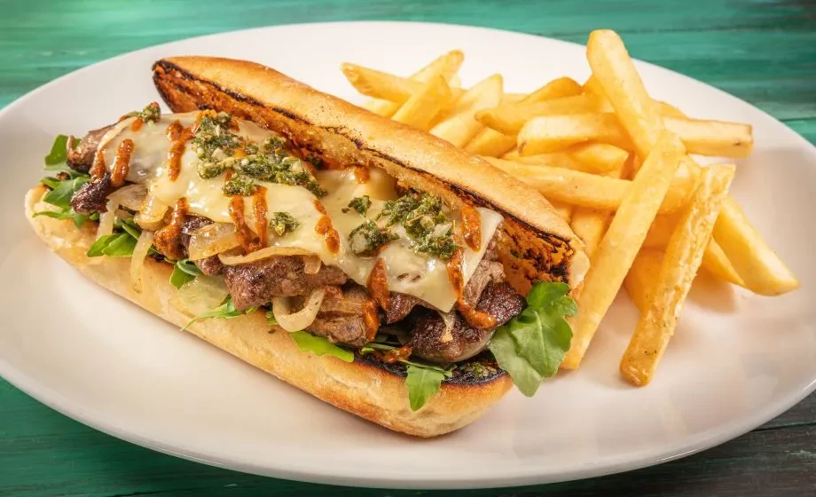 Meat and cheese sub with arugula, two sauces, and french fries.