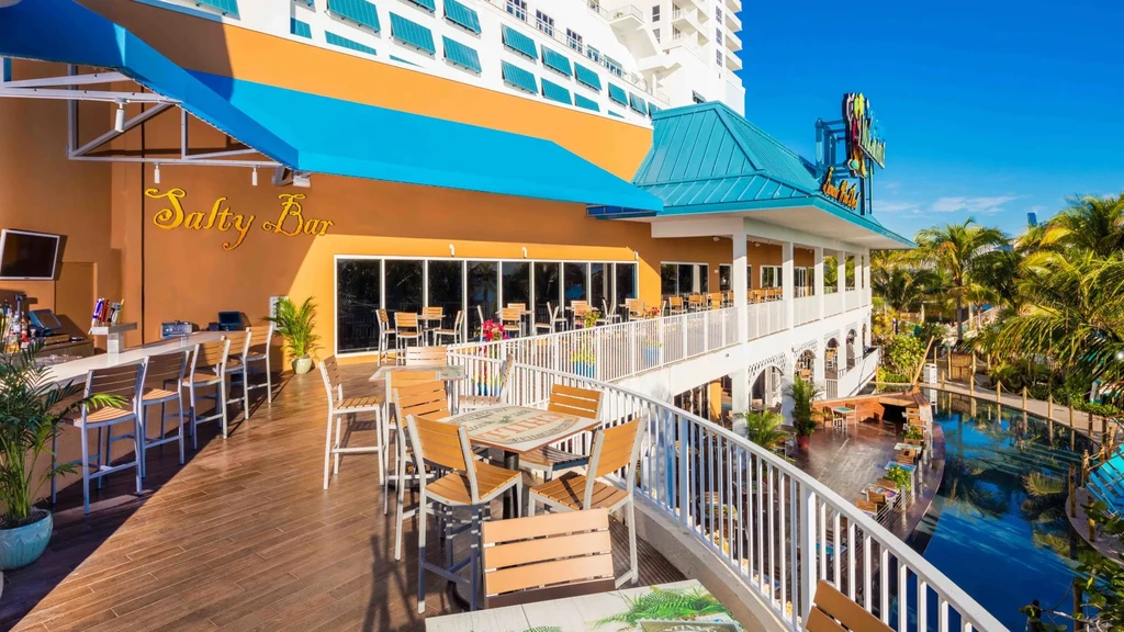 Outdoor 'Salty Bar' building with deck, palm trees, and blue water.