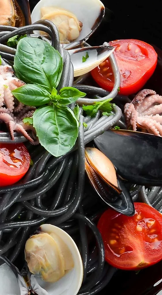 Squid ink pasta with mussels, clams, octopus, tomatoes, and basil.
