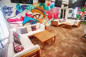 Vibrant lounge area with white sofas and graffiti art, including 'Burger Freaks'.