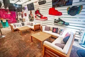 Modern restaurant lounge with sofas, tables, and large sneaker art.