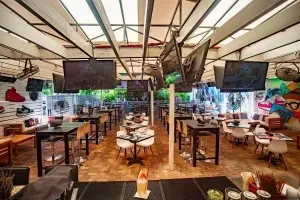 Modern sports bar patio with TVs, varied seating, and colorful graffiti.