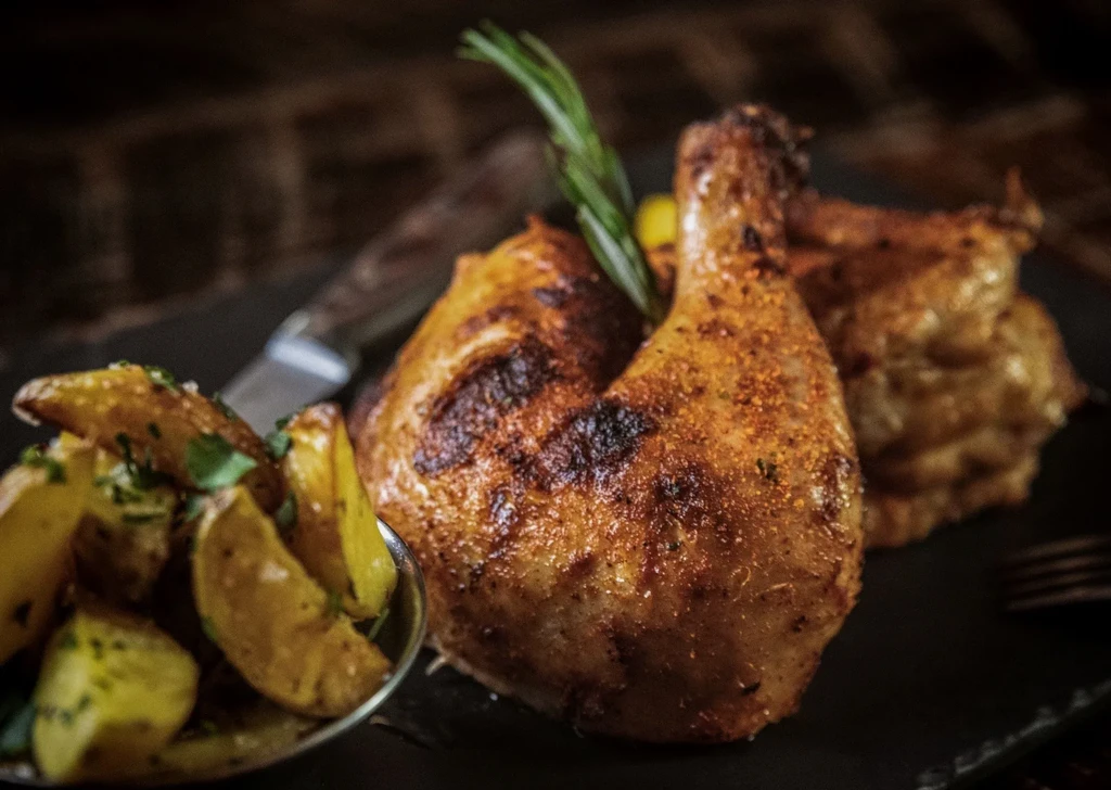Grilled chicken with rosemary, and herb-seasoned roasted potato wedges.