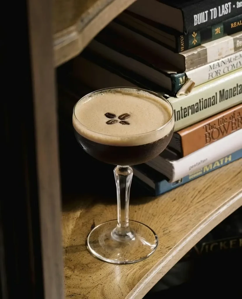 Espresso Martini in a coupe glass with coffee beans and books.