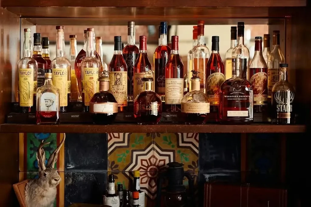 Well-stocked whiskey and bourbon shelf with patterned tiles and jackalope.