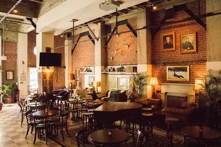 Cozy, sophisticated industrial-chic lounge with grand piano and brick walls.