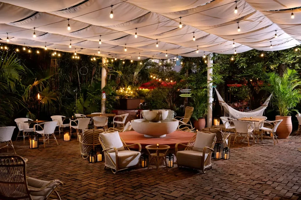 Illuminated outdoor garden patio with fountain, plants, and seating.
