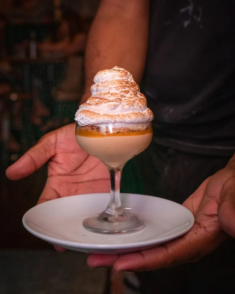 Layered dessert in a stemmed glass with creamy base and toasted meringue.
