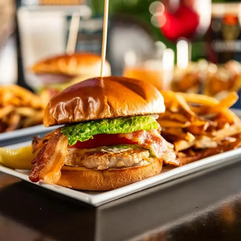Burger with bacon, fries, and pickle spear in a restaurant.