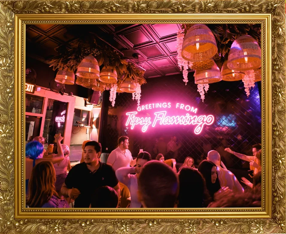 Lively bar with pink and purple neon, "Tipsy Flamingo" sign, and people.