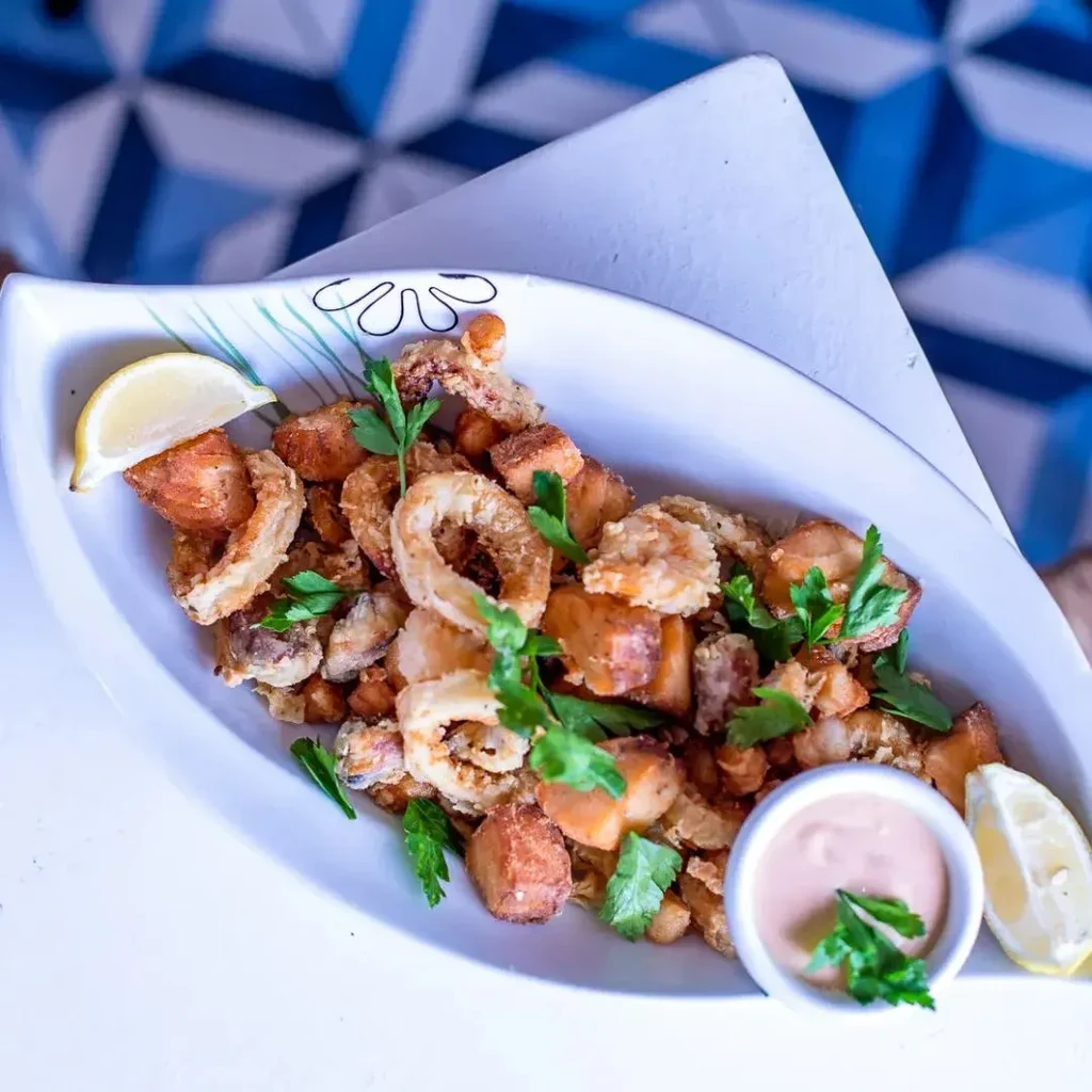 Leaf-shaped dish of fried calamari, shrimp, potatoes, and dipping sauce.