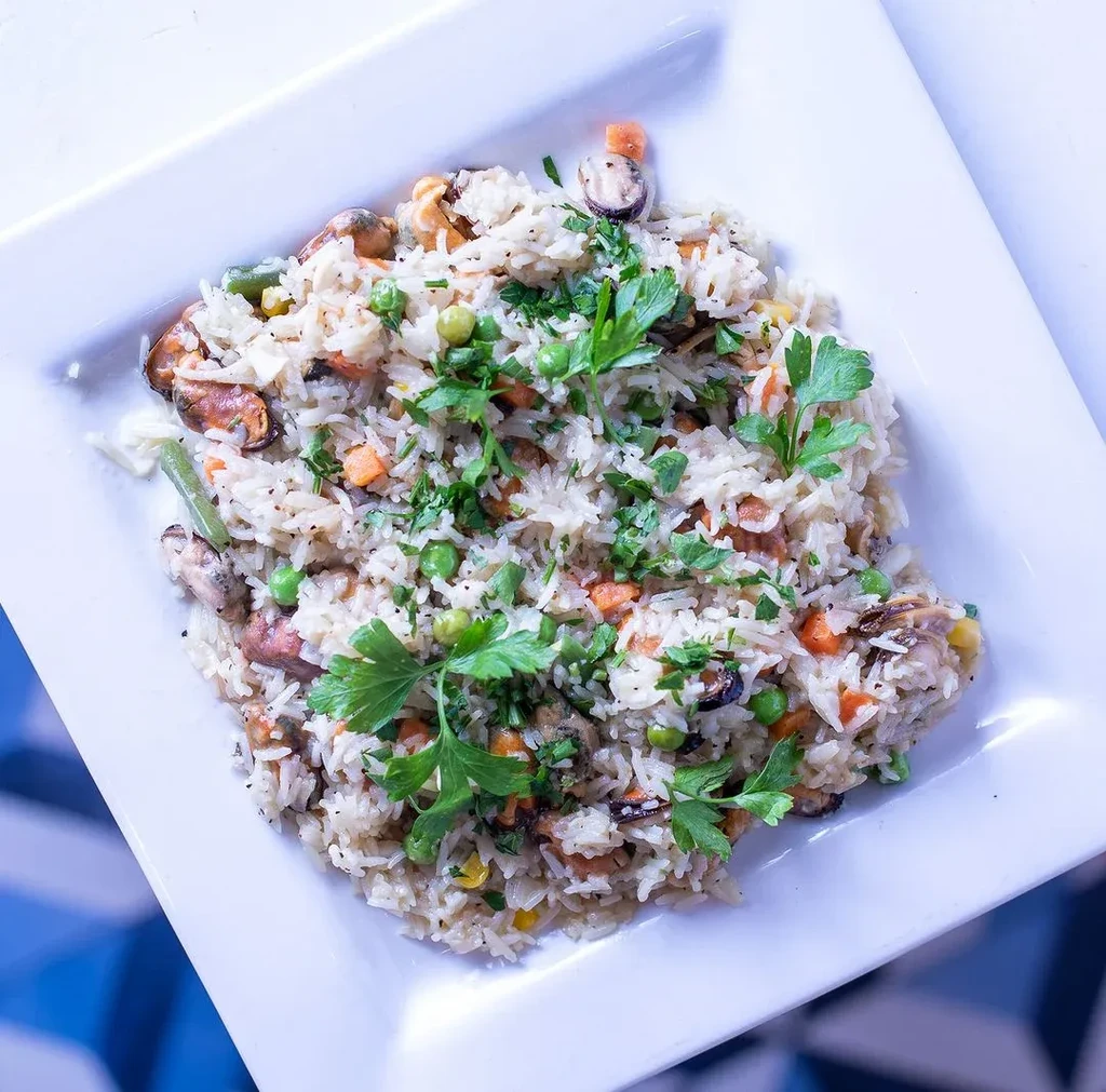 Overhead: Seafood and vegetable rice with mussels and parsley.