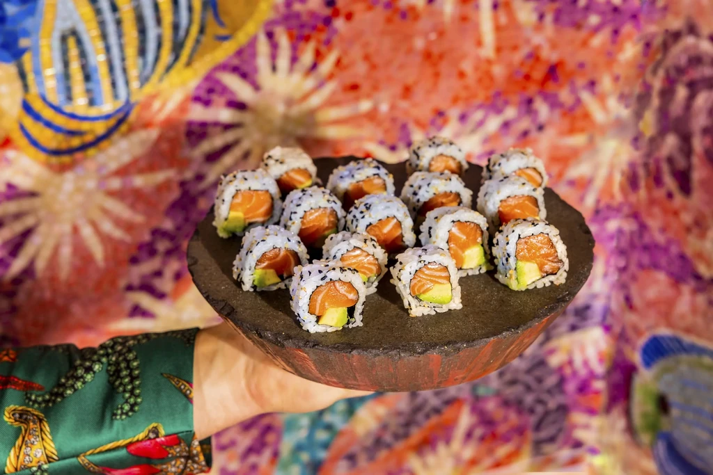 California rolls with salmon and avocado on rustic platter, vibrant background.