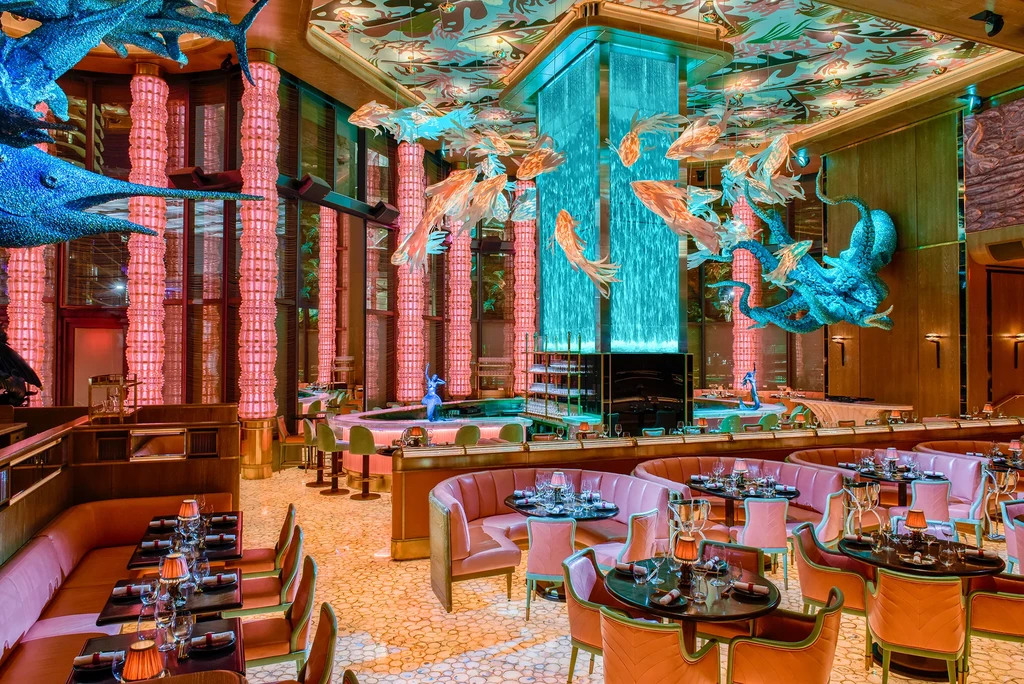Luxurious aquatic restaurant interior with turquoise waterfall and marine sculptures.