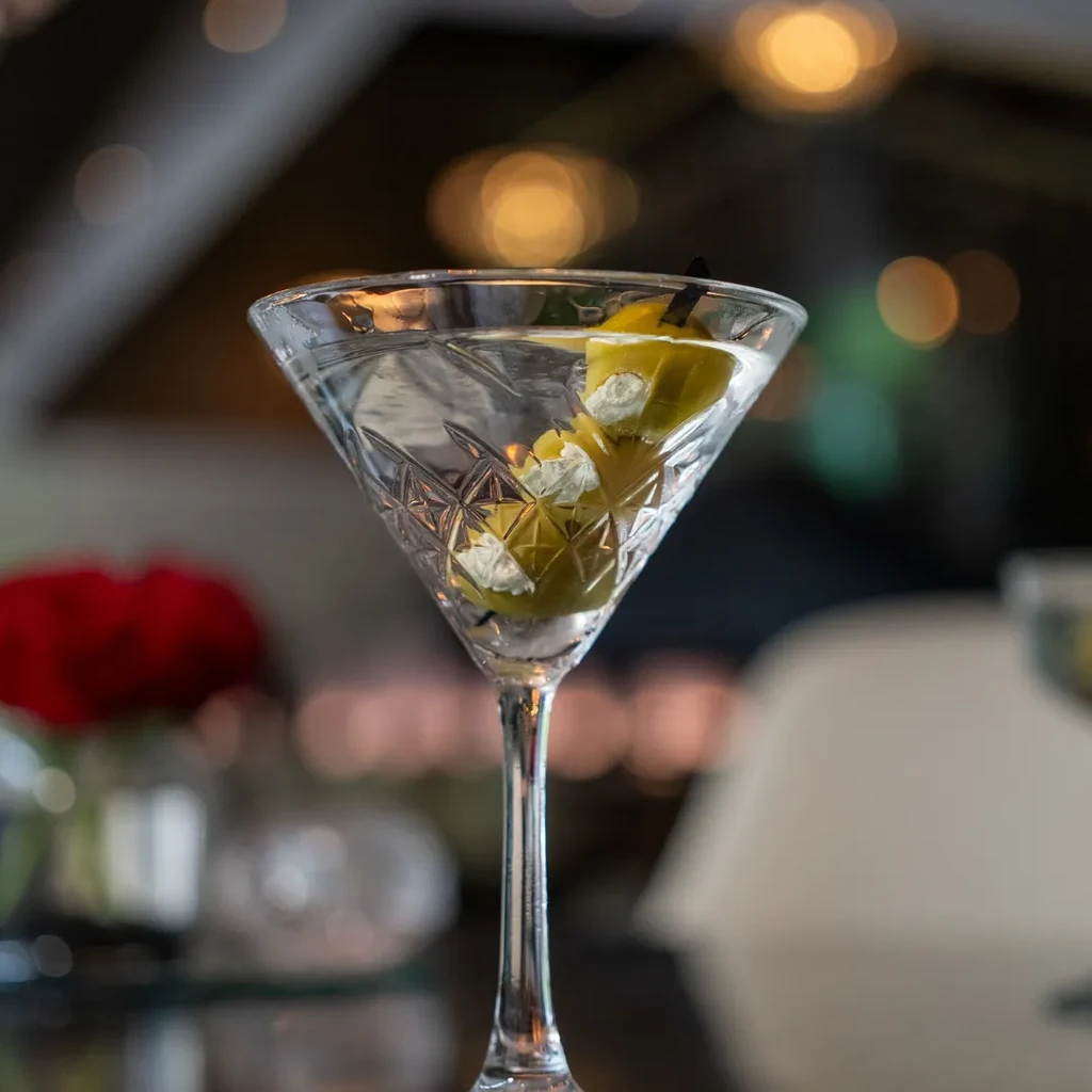 Close-up of a martini in a cut-glass with two skewered green olives.