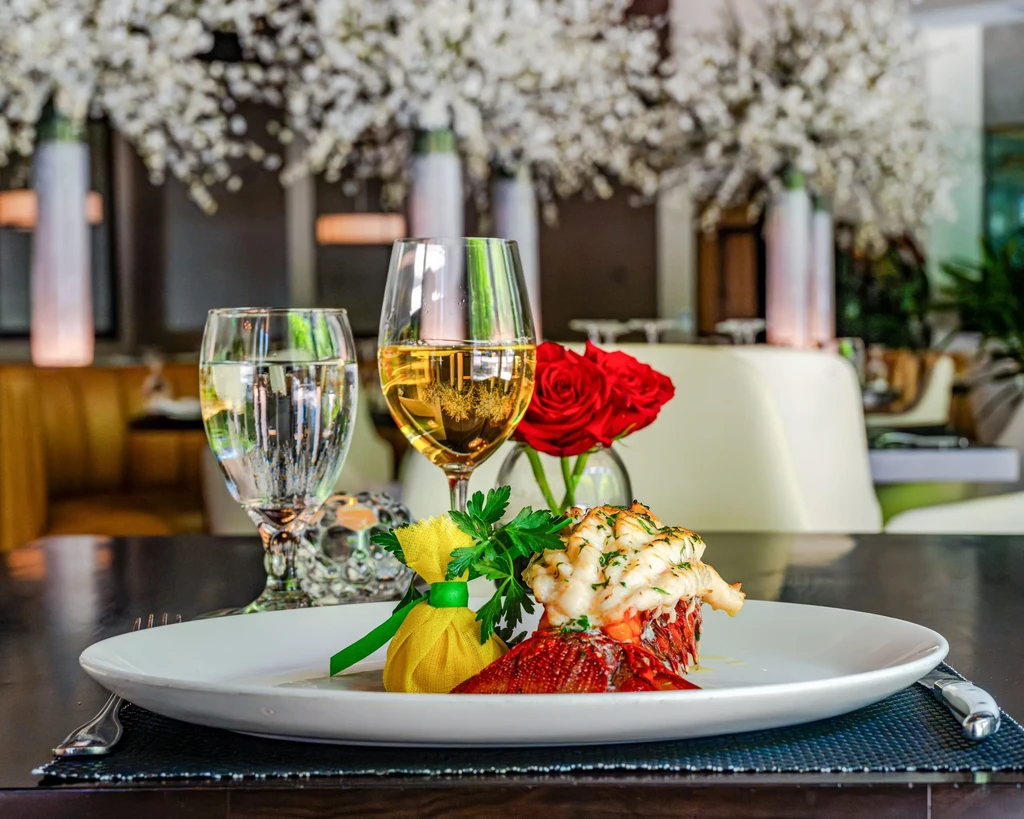 Plated cooked lobster tail, wine, and water in an upscale restaurant.