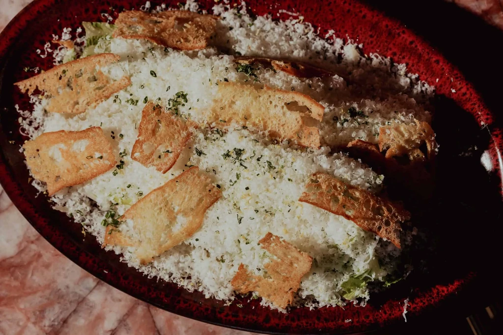 Overhead salad with grated cheese, golden croutons, and green herbs.