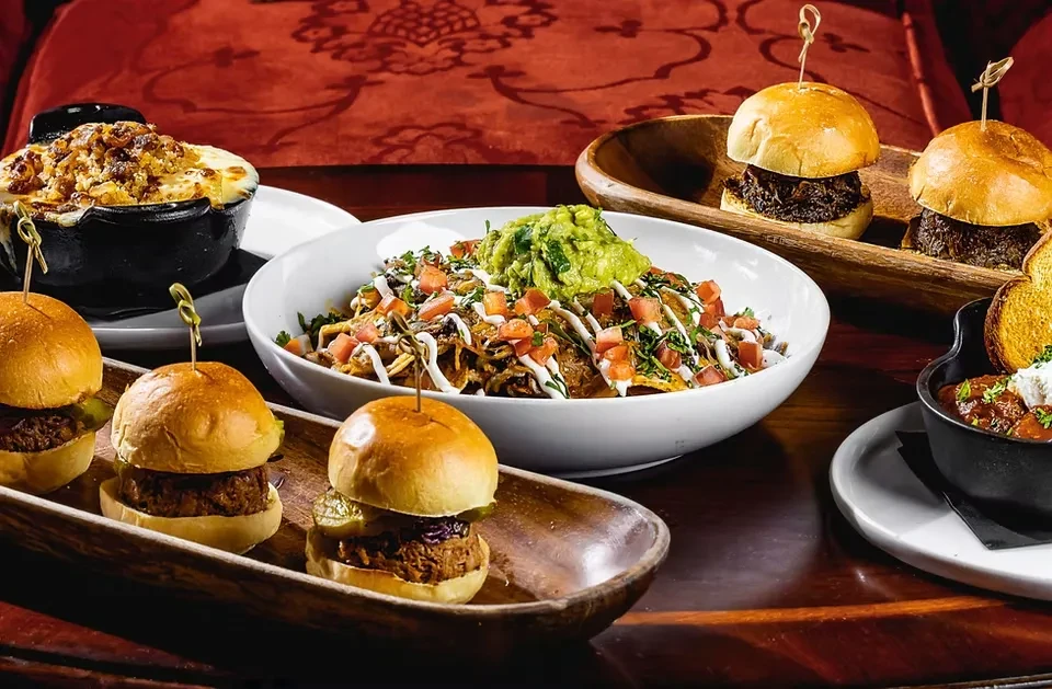 Table laden with mini sliders, mac and cheese, nachos, and chili.