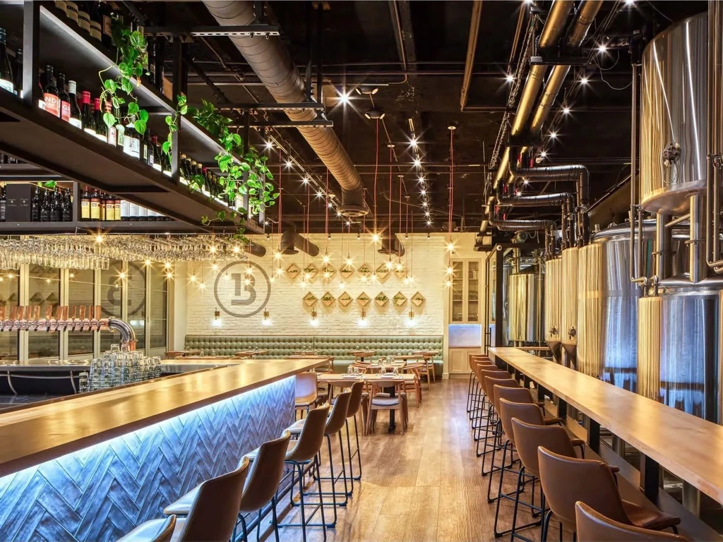 Modern brewpub interior with a bar, dining area, and gleaming fermentation tanks.