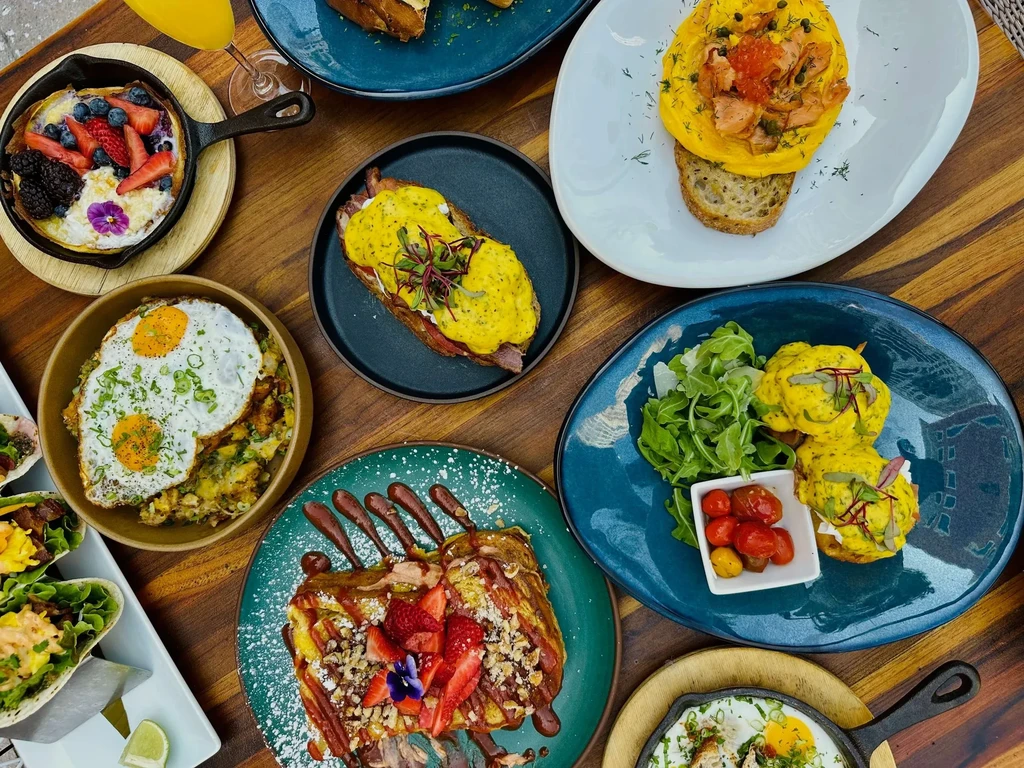 Diverse gourmet breakfast and brunch dishes on a wooden table.