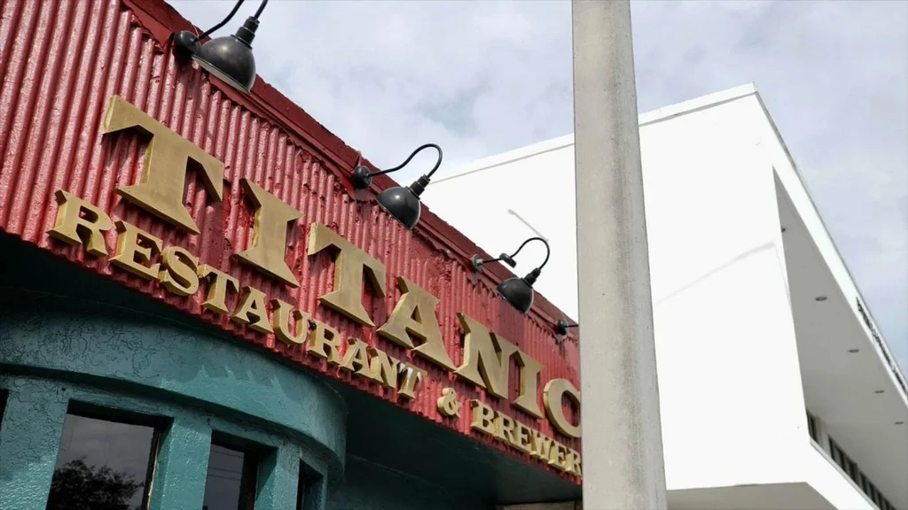 Upward view of gold Titanic Restaurant & Brewery sign on red metal.