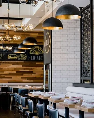 Dining room with wood tables, dome pendant lights and tile walls