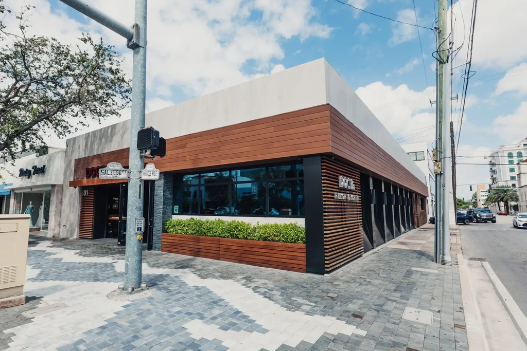 Modern 'DOCE FRESH KITCHEN' restaurant exterior with wood, stone, and glass.