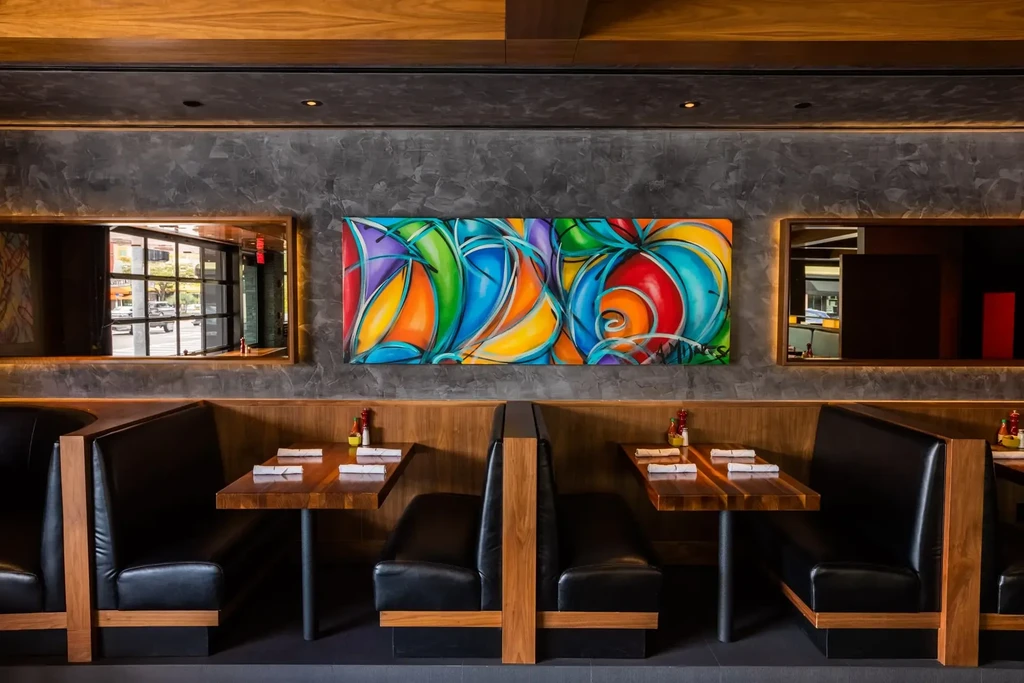 Modern restaurant interior with leather booths and a vibrant abstract painting.