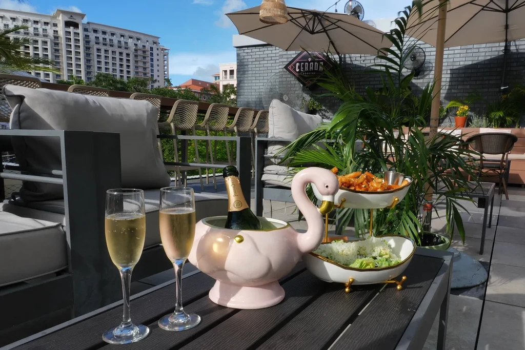 Rooftop table with champagne, flamingo ice bucket, appetizers, and salad.