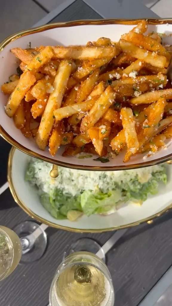 Top-down: Two-tiered dish with parmesan fries, green salad, and sparkling wine.
