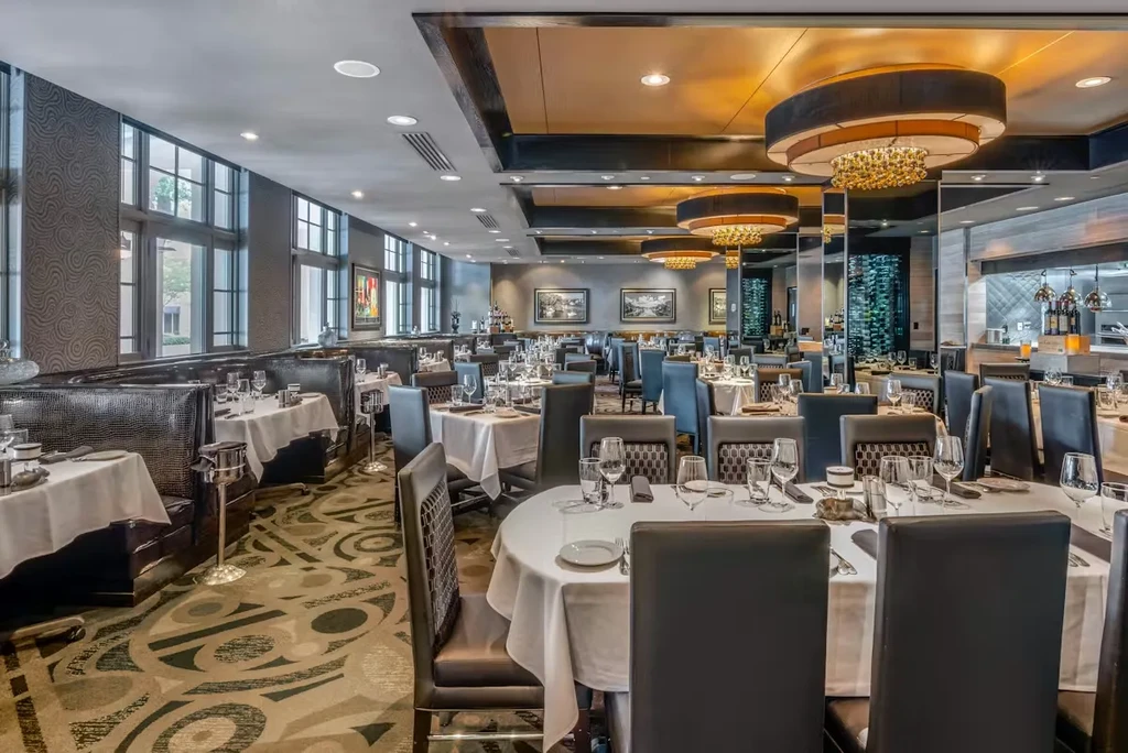 Sophisticated empty restaurant dining room with set tables and crystal chandeliers.