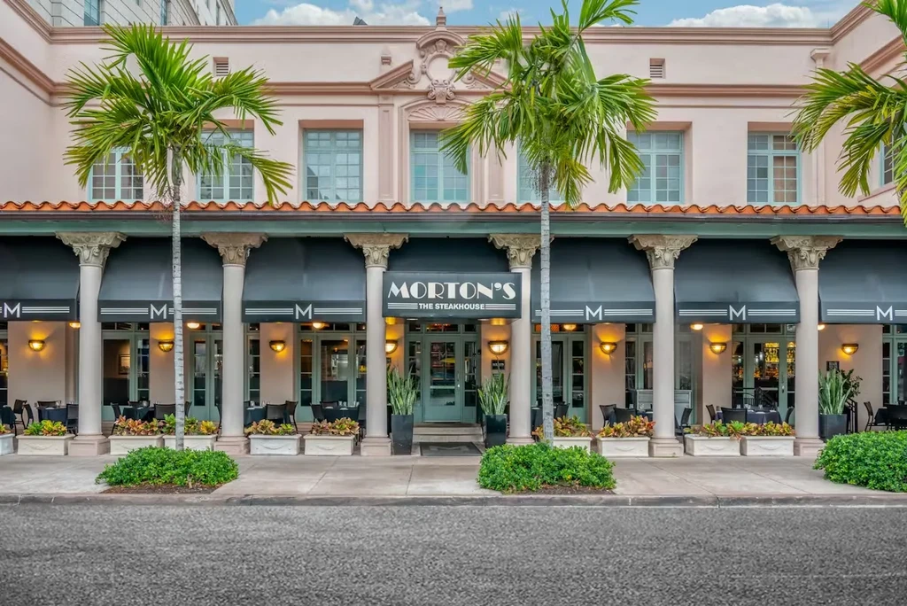Morton's The Steakhouse exterior: peach building, dark awnings, classical pillars.
