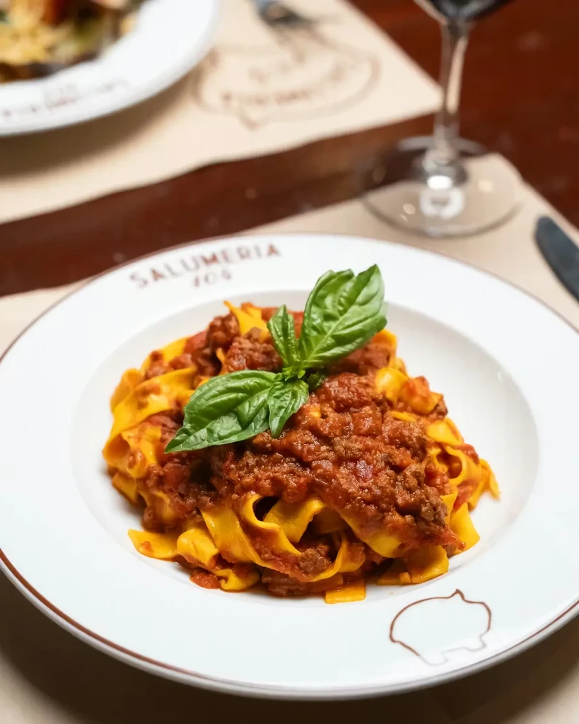Top-down view of tagliatelle pasta with Bolognese sauce and basil.